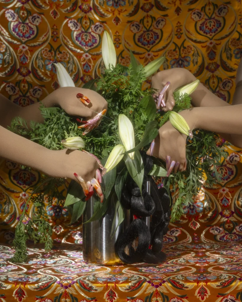 Jamie Ho’s work layers floral arrangements with disembodied hands and braided hair, blending beauty with unease in “magic mirrors” at Art League Houston. (Photo courtesy Art League Houston)