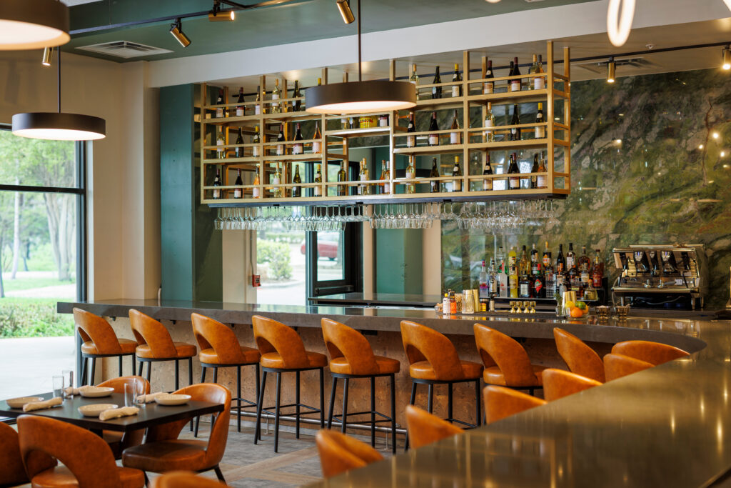 Created by Dallas-based Hohe Design Group in collaboration with Ashley Odeh, Trattoria Bugatti's design blends contemporary elements with subtle nods to the original Bugatti, including layered shades of green, curated vintage artwork, and a sleek modern bar that anchors the space. (Photo by Samantha Marie Photography)